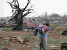 A woman carries her child through a field near the collapsed Plaza Towers Elementary School in Moore, Okla., on Monday A tornado as much as a mile wide with winds up to 200 mph roared through the Oklahoma City suburbs flattening entire neighborhoods, setting buildings on fire and landing a direct blow on an elementary school.