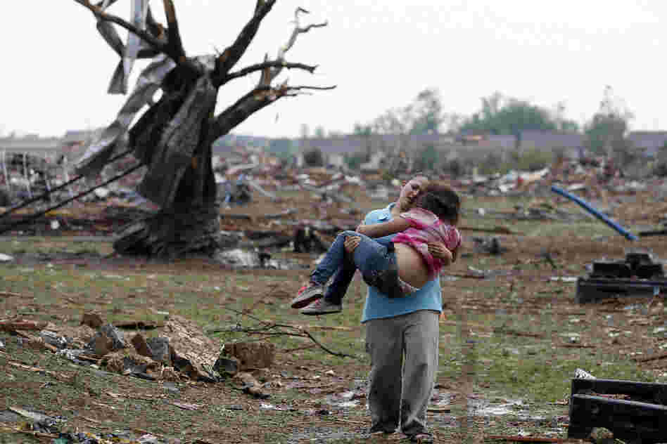 A woman carries her child through a field near the collapsed Plaza Towers Elementary School. The tornado flattened entire neighborhoods and set buildings on fire.