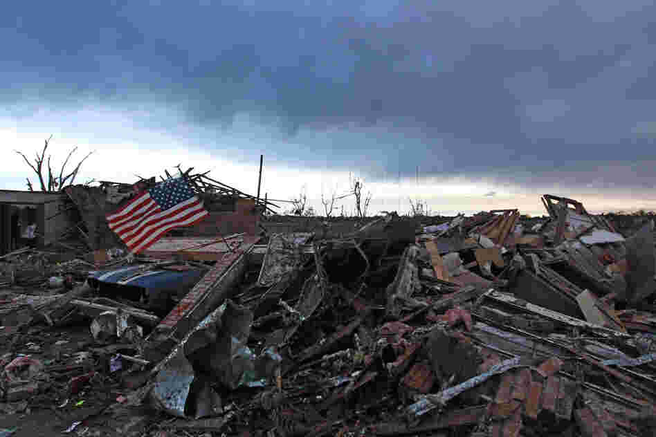 An American flag blows in the wind at sunrise atop the rubble of a home Tuesday, a day after a monstrous tornado moved through the Oklahoma City suburb of Moore, Okla. 