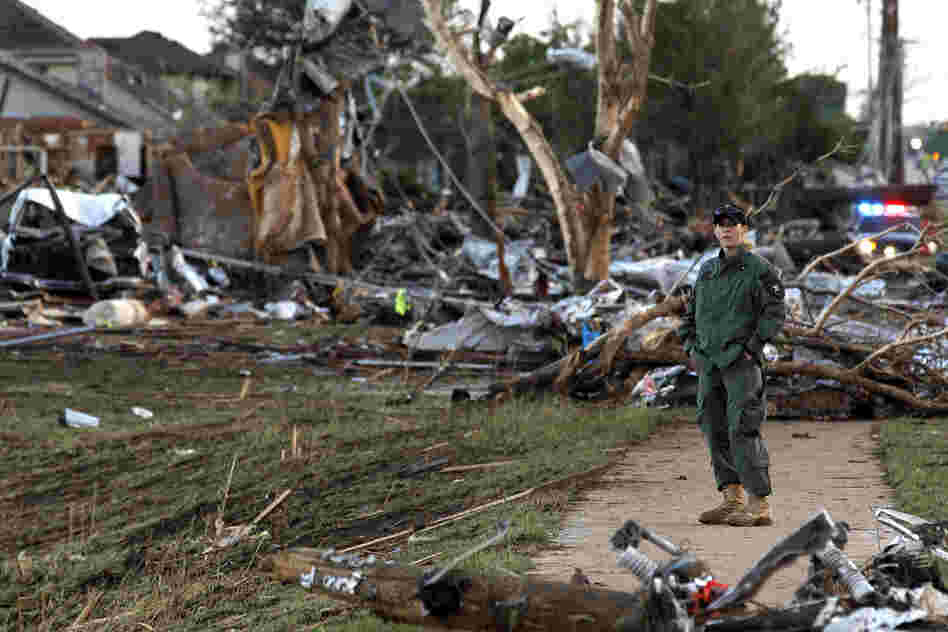 A member of a security team helps guard an area of rubble from a destroyed residential neighborhood on Tuesday in Moore, Okla. The huge tornado roared through the Oklahoma City suburb Monday, flattening entire neighborhoods and destroying an elementary school with a direct blow as children and teachers huddled against the winds. 
