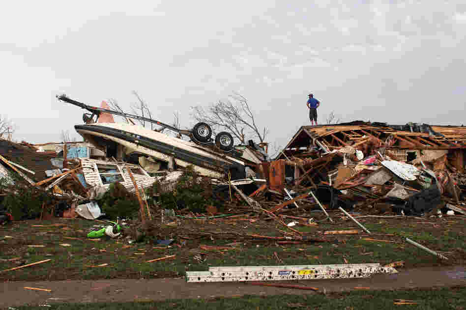 A man surveys tornado damage from a roof in Moore, Okla., on Monday. The death toll from the massive twister is expected to rise.
