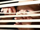 Boy looking through window blinds Boy looking through window blinds