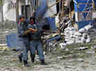 A wounded Afghan police officer is helped from the scene of Friday's explosion and gunfire in Kabul.