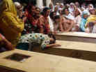 A relative of one of the children who died after a fire on a school bus, cries over the coffin, on the outskirts of Gujrat.