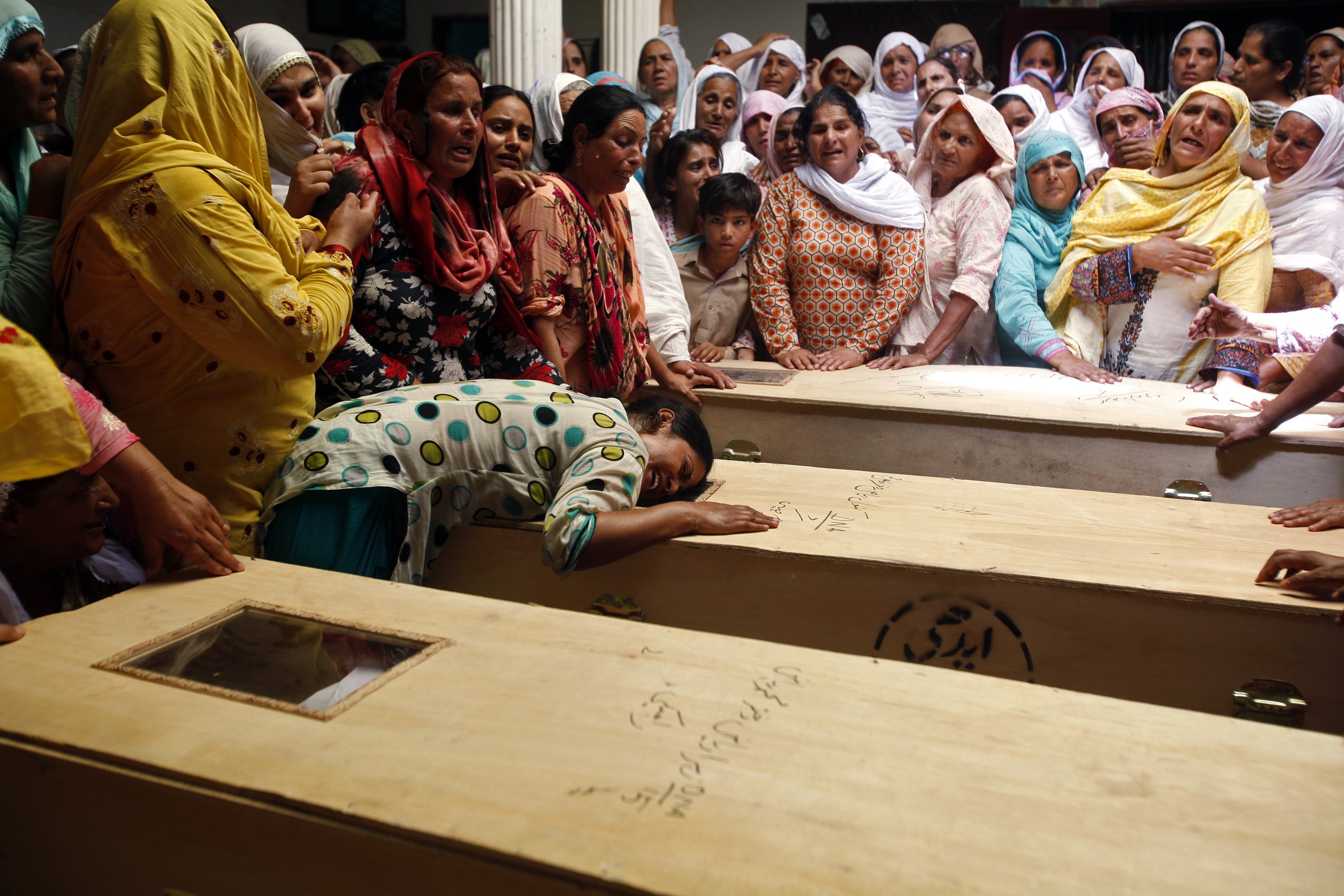 A relative of one of the children who died after a fire on a school bus, cries over the coffin, on the outskirts of Gujrat.