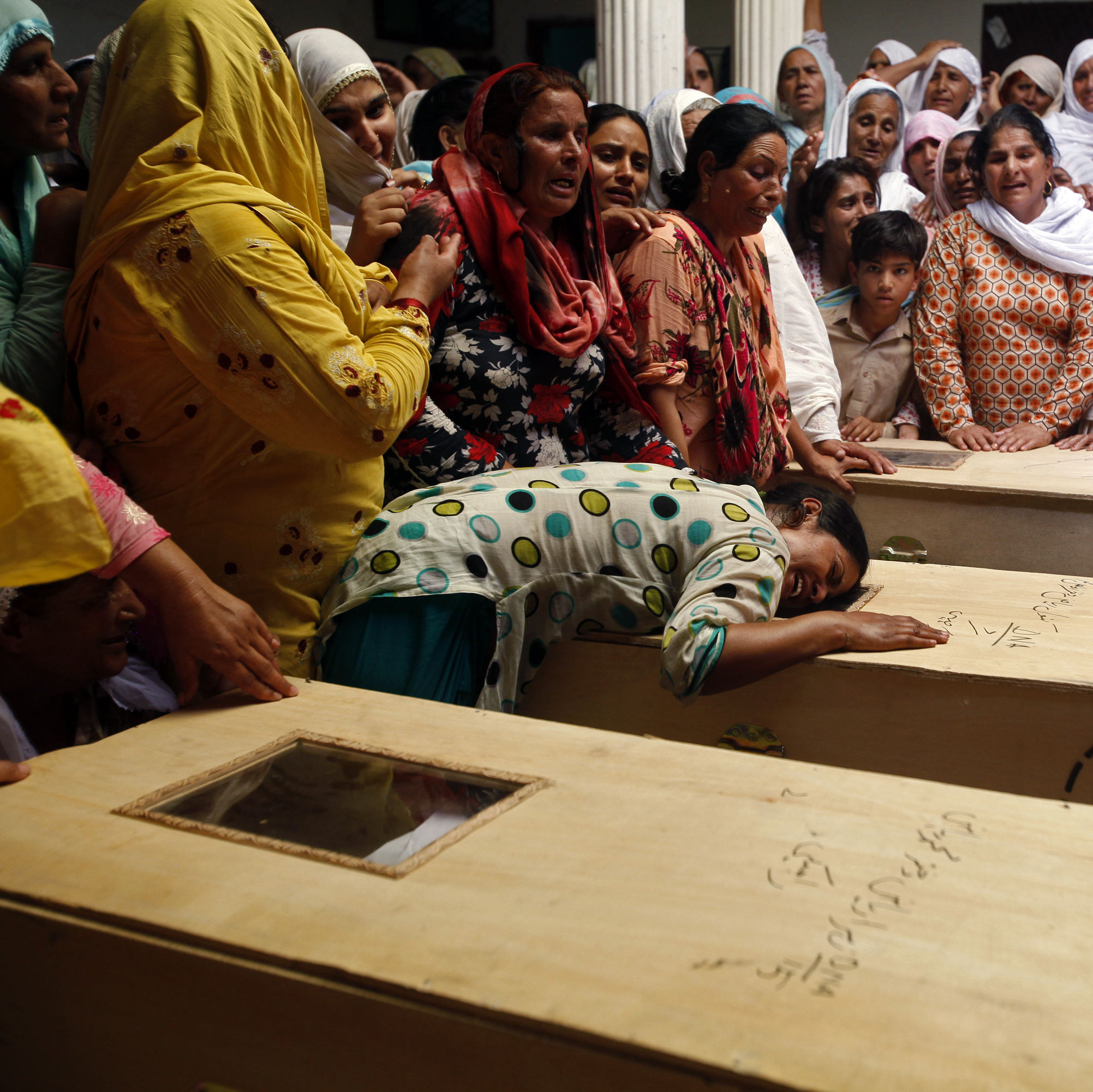 A relative of one of the children who died after a fire on a school bus, cries over the coffin, on the outskirts of Gujrat.