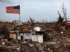 An American flag flies over the rubble of a destroyed neighborhood on May 24 in Moore, Okla.
