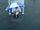A man finds some shelter from the rain Thursday at the U.S. Open, which is being played at Merion Golf Club in Ardmore, Pa.