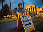 Election Day volunteer Vicki Groff places a sign to direct voters to a polling station at Kenilworth School in Phoenix in 2012.