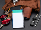 Personal organizer with blank lined page propped against various items spilling out of a brown leather purse. Studio isolated on a black textured background. Personal organizer with blank lined page propped against various items spilling out of a brown leather purse. Studio isolated on a black textured background.