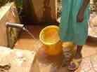 Rodan Gatia gets water from a spring. A chlorine dispenser is behind her. Rodan Gatia gets water from a spring. A chlorine dispenser is behind her.