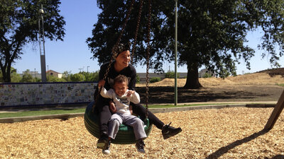 Micaela Torres and 2-year-old Jakai Johnson swing underneath a surveillance camera at Miwok Park in Elk Grove, Calif. The city's police department collects more than 100 video feeds from across the city.