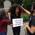 Model Malliha Ahmad holds a sign inviting passersby to touch her hair. Model Malliha Ahmad holds a sign inviting passersby to touch her hair.