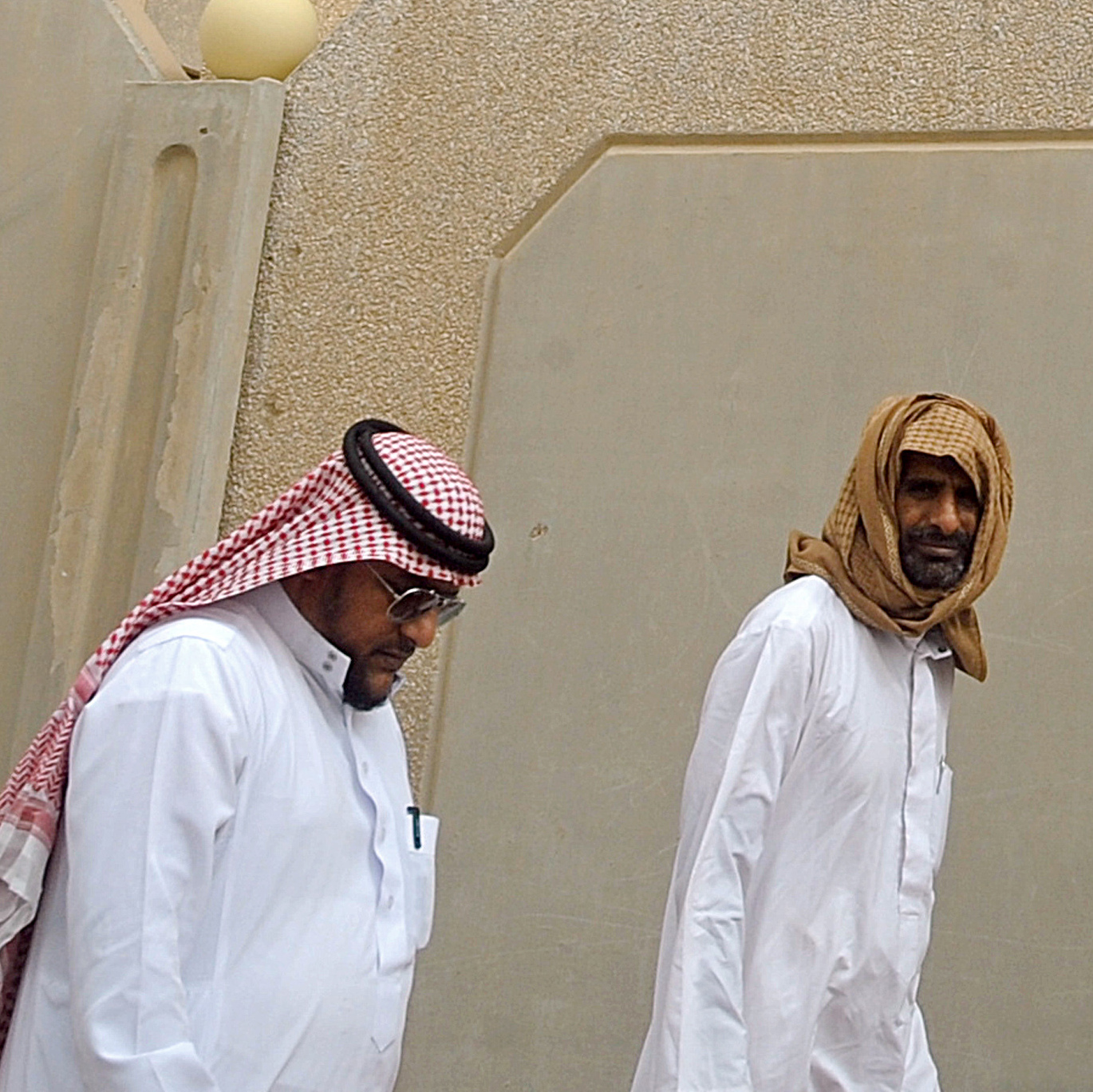 Saudi men walk to the King Fahad hospital in the city of Hofuf on Sunday. In eastern Saudi Arabia, where outbreaks of the MERS virus have been concentrated, people have resumed their habits of shaking hands and kissing.