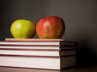 Two apples sit on a stack of books. Two apples sit on a stack of books.