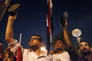 Protesters watch Morsi's speech near the presidential palace in Cairo. Morsi told Egyptians that he had been freely elected a year ago, and that he intends to carry out his duties.