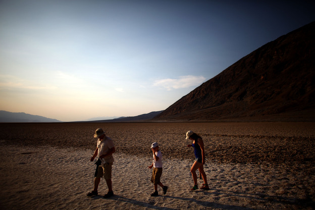 Tourists walk across the Badwater Basin, which sits 282 feet below sea level, in Death Valley, Calif., on June 30. People from around the world flock to the area to experience temperatures that rise to the high 120s on a regular basis. (Image credit: NPR)
