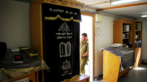 An Israeli soldier in a platoon reserved for the ultra-Orthodox leans on the doorway of the unit's makeshift synagogue. The military accommodates the religious needs of ultra-Orthodox soldiers by allowing time for Torah study and prayers three times daily.