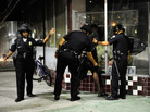 Los Angeles Police Department officers in riot gear detain a man after disturbances in the streets around Leimert Park. Los Angeles Police Department officers in riot gear detain a man after disturbances in the streets around Leimert Park.