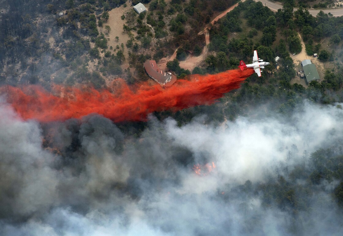 An aircraft lays down a line of fire retardant between a wildfire and homes in the dry, densely wooded Black Forest area northeast of Colorado Springs, Colo., on June 13.