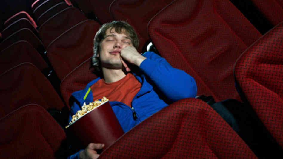 A man sleeps in a movie theater. A man sleeps in a movie theater.