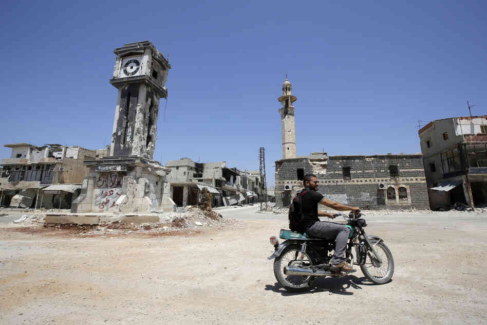 A Syrian man rides his motorbike past the Sunni Grand mosque on Thursday in the city of Qusayr, in Syria's central Homs province. A Syrian man rides his motorbike past the Sunni Grand mosque on Thursday in the city of Qusayr, in Syria's central Homs province.