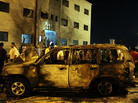 Libyans gather near a burned-out vehicle after an attack outside the courthouse in Benghazi on July 28, the day after more than 1,000 inmates escaped during a prison riot. Libyans gather near a burned-out vehicle after an attack outside the courthouse in Benghazi on July 28, the day after more than 1,000 inmates escaped during a prison riot.