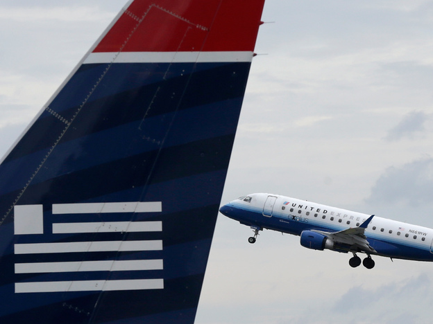 A United Airlines jet takes off behind a US Airways jet at Ronald Reagan Washington National Airport on Tuesday. (Image credit: Getty Images)