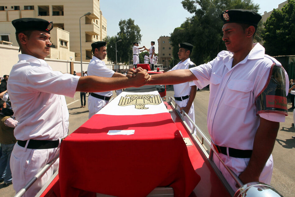 Egyptian police officers join hands during a funeral procession of one their colleagues, who was killed during clashes with Morsi supporters.