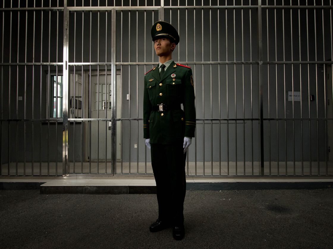 A paramilitary guard stands before the bars of a main gate to a detention center during a government guided tour in Beijing last year.