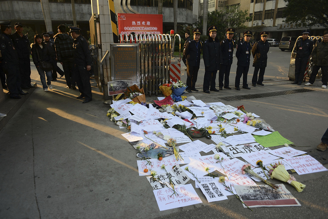 Security guards stand outside newspaper offices in Guangdong province in January, where banners and flowers were laid in protest of censorship.