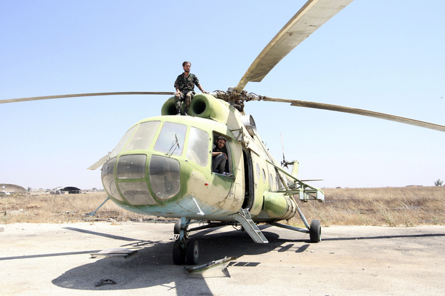 The U.S. is considering adding helicopters to its list of potential targets of a military strike. Here, rebel fighters are seen on a Russian-made helicopter seized from the Syrian army at the Minnig Military Airport near the Turkish border on Aug. 11. (Image credit: Reuters/Landov)