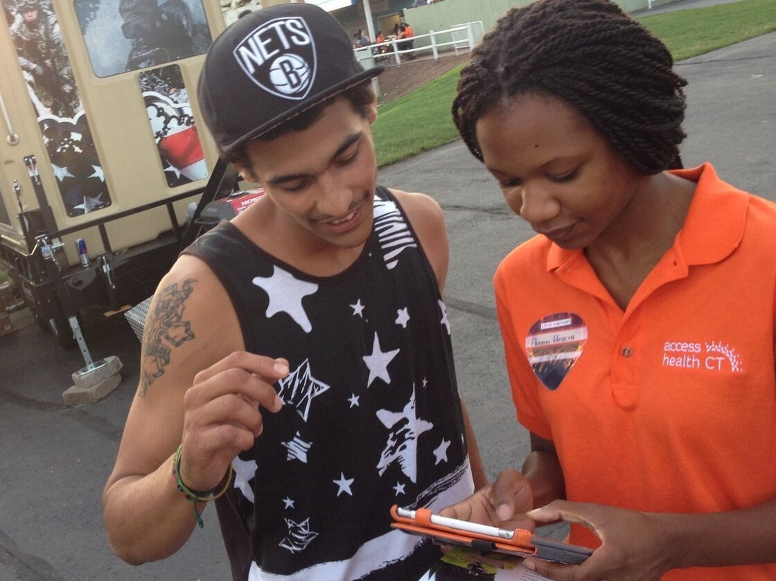 Outreach worker Emanuela Cebert (right) talks to Papilon Ferreiras about health insurance outside a rap concert.