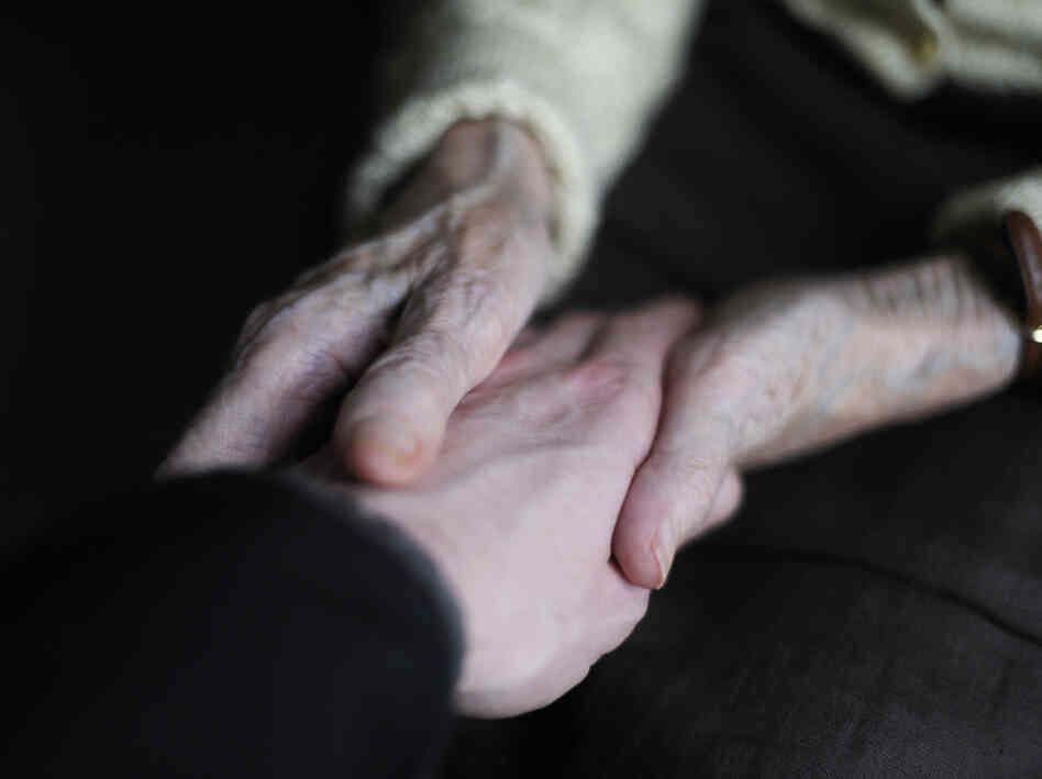 A woman suffering from Alzheimer's disease holds the hand of a relative in a retirement house in Angervilliers, France. A woman suffering from Alzheimer's disease holds the hand of a relative in a retirement house in Angervilliers, France.