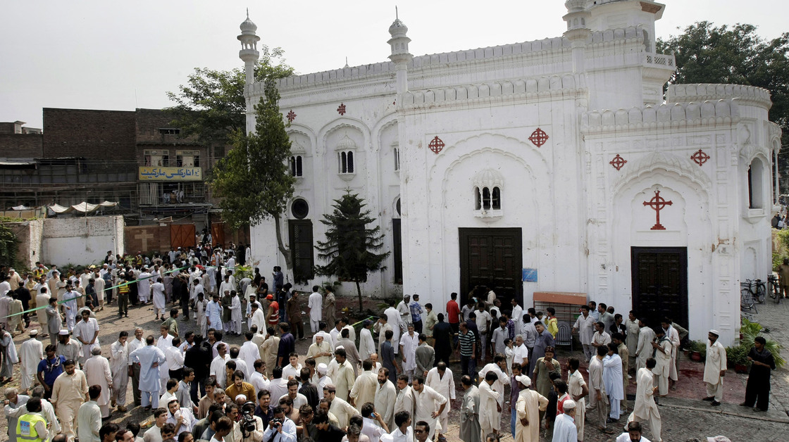People gather outside All Saints Church in Peshawar, Pakistan, Sunday, after a suicide bombing attack killed scores of people earlier in the day, officials said.