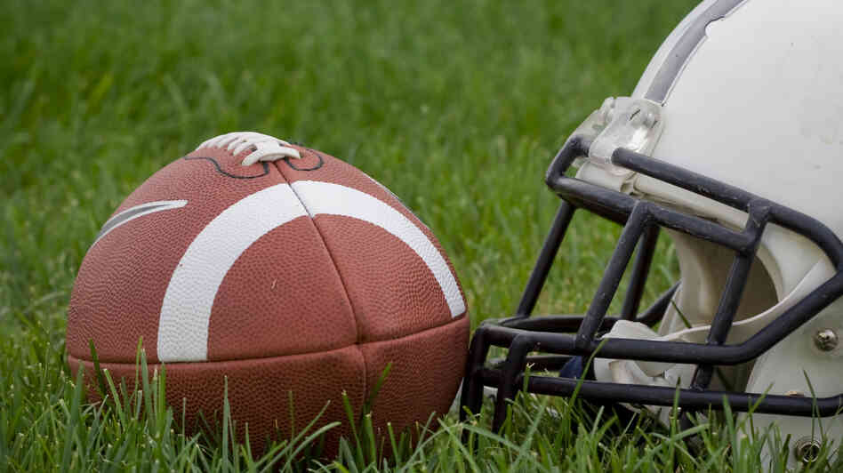 An American football and a helmet on a grass field An American football and a helmet on a grass field