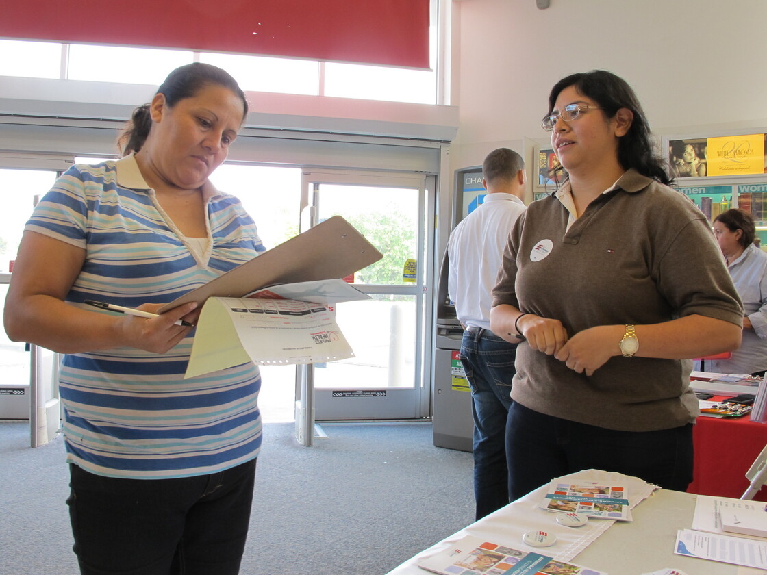 Enroll America outreach worker Rosy Mota (right) talks about the federal health care law with a CVS customer.