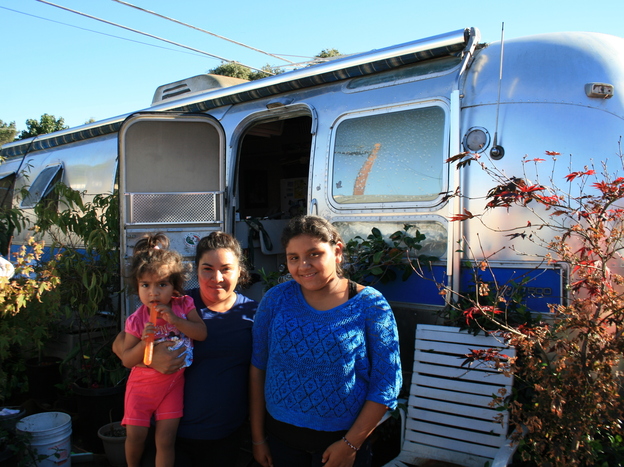 Palo Alto middle school student Jennifer Munoz Tello (right) stands outside her family's trailer in Palo Alto with her mother, Sandra, and 2-year-old sister, Cynthia. (Image credit: NPR)