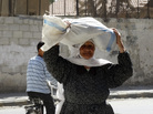 A woman carries a sack of food aid on her head in Ghouta, Syria, earlier this month. A woman carries a sack of food aid on her head in Ghouta, Syria, earlier this month.