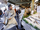 A fishmonger tosses a just-purchased fresh salmon to a colleague behind the counter at the Pike Place Fish Market in Seattle. A fishmonger tosses a just-purchased fresh salmon to a colleague behind the counter at the Pike Place Fish Market in Seattle.