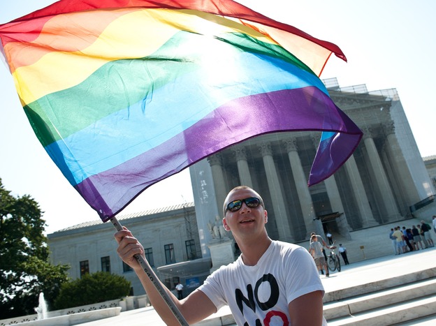 A gay rights activist waves a rainbow flag in front of the U.S. Supreme Court in June, a day before the ruling on the Defense of Marriage Act. (Image credit: AFP/Getty Images)