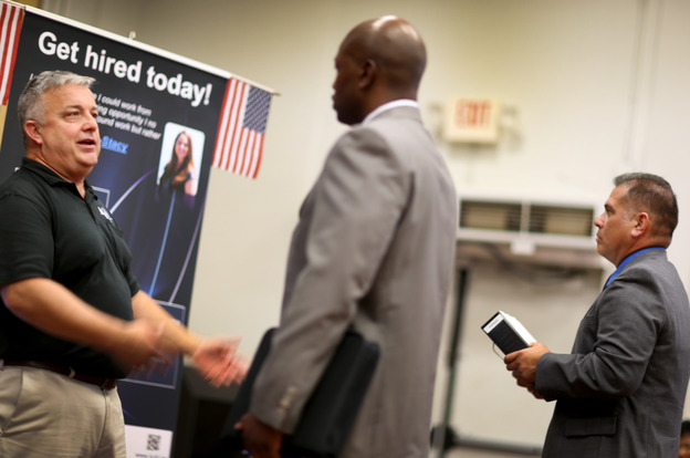 Hans Kahl (left) speaks with prospective employees at a job fair for veterans, in Miami on Tuesday. With job growth still slow, the Federal Reserve may keep trying to stimulate the economy. (Image credit: Getty Images)