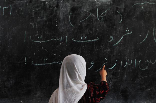 An Afghan child writes on a blackboard as she attends classes in a school built by German troops at a refugee camp in the outskirts of Mazar-e-Sharif on April 19. The number of students enrolled in Afghan schools has skyrocketed since the fall of the Taliban at the end of 2001. (Image credit: AFP/Getty Images)