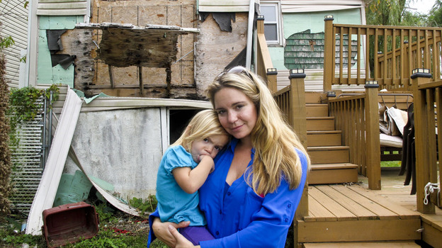 Samantha Langello and her daughter Alanna, 2, stand in front of their flood-damaged house in Fox Beach on Staten Island, N.Y. (Image credit: NPR)