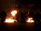 People ride bikes by a car on fire in a highway in Sao Paulo on Tuesday. People ride bikes by a car on fire in a highway in Sao Paulo on Tuesday.