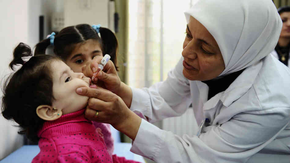 A health worker administers polio vaccine as part of a UNICEF-supported campaign in Damascus. Aid agencies sometimes have to negotiate with rebel groups and work in dangerous situations to immunize vulnerable children. A health worker administers polio vaccine as part of a UNICEF-supported campaign in Damascus. Aid agencies sometimes have to negotiate with rebel groups and work in dangerous situations to immunize vulnerable children.
