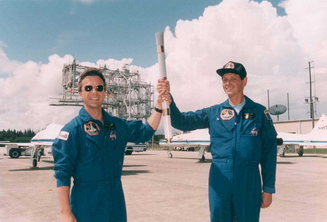 Payload specialists Robert Brenton Thirsk, left, and Jean-Jaques Favier hold the Olympic torch they brought to space aboard Space Shuttle Columbia in 1996.