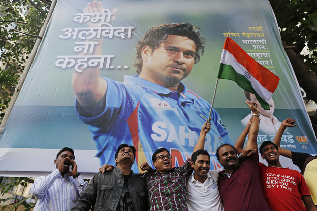 Cricket fans holding an Indian national flag cheer in front of a billboard of superstar cricketer Sachin Tendulkar outside a stadium in Mumbai on Thursday. India's favorite son dominated the sport for nearly a quarter of a century. Now, that fabled career is coming to a close. (Image credit: Reuters /Landov)