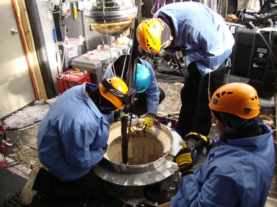 After the sensors are threaded onto the cable, the IceCube deployment team lowers them into the hole. After the sensors are threaded onto the cable, the IceCube deployment team lowers them into the hole.