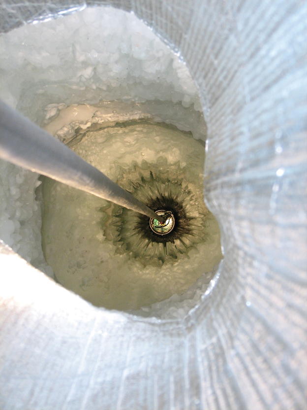 A digital optical module sensor is being lowered into a hole in the Antarctic ice. The IceCube detector on the continent consists of 86 strings of sensors, each strung deep down below the surface. (Image credit: IceCube/NSF)